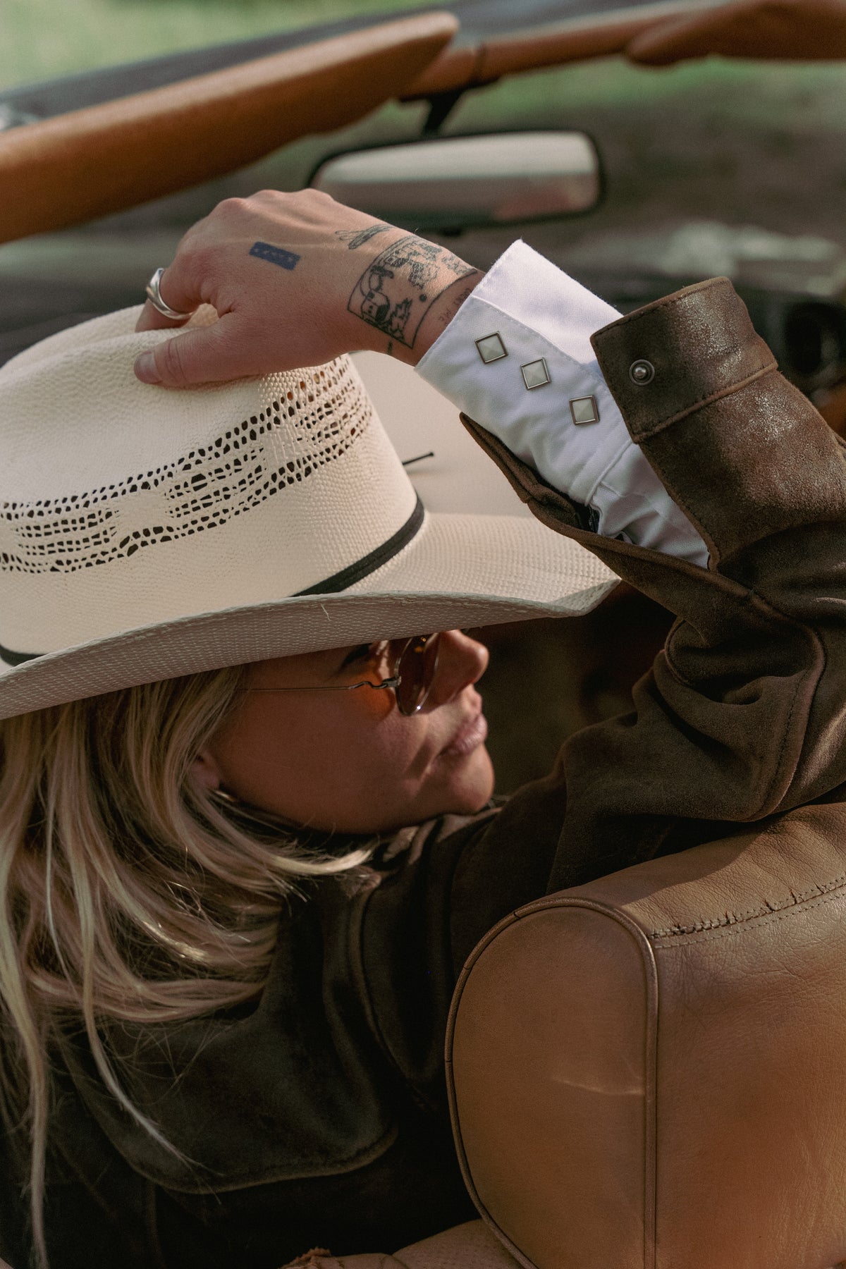 Vintage western shirt with embroidered floral fringe, held near a person wearing a cowboy hat